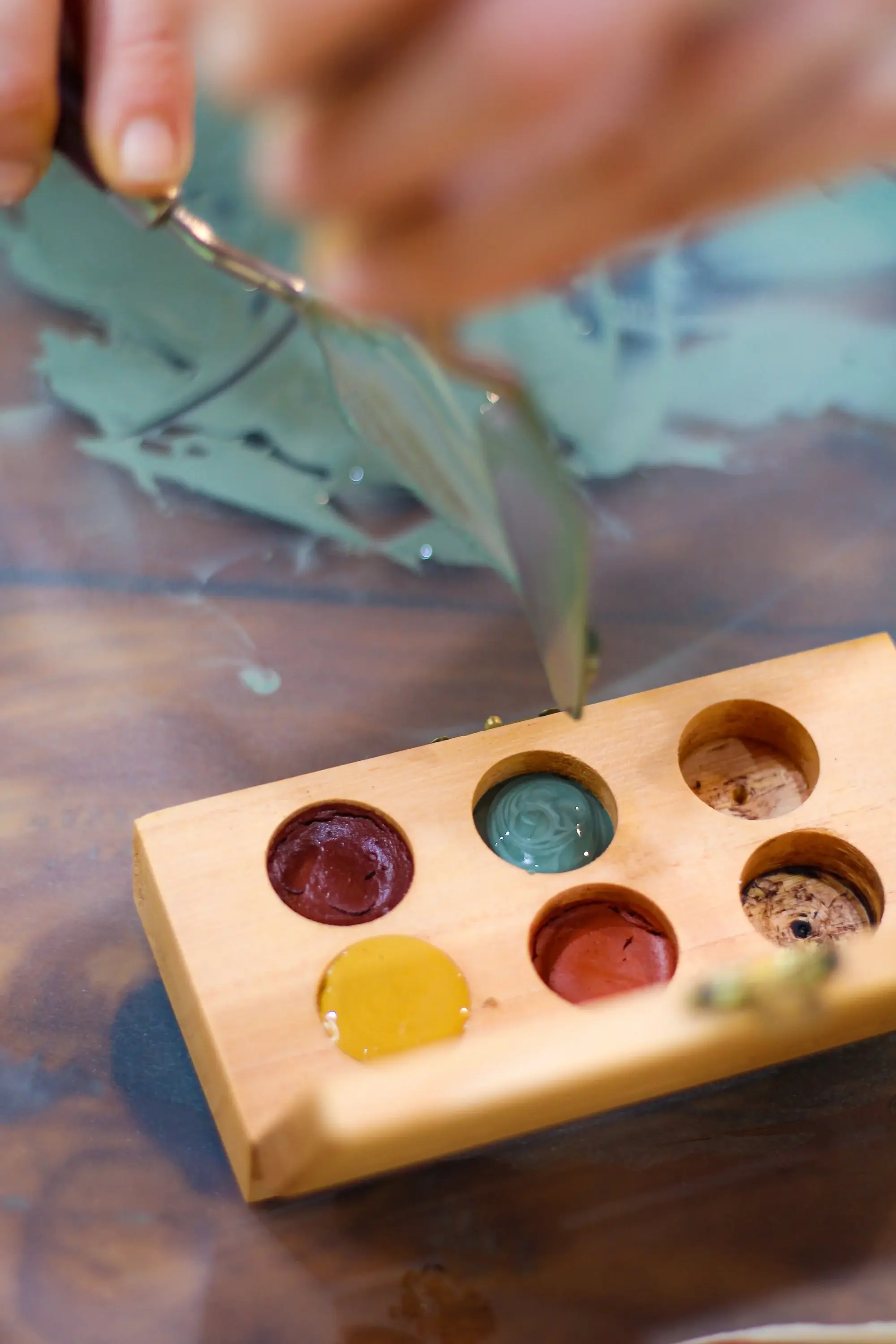 Paleta de madeira com aquarelas de terra em vermelho, amarelo, verde-azulado e marrom