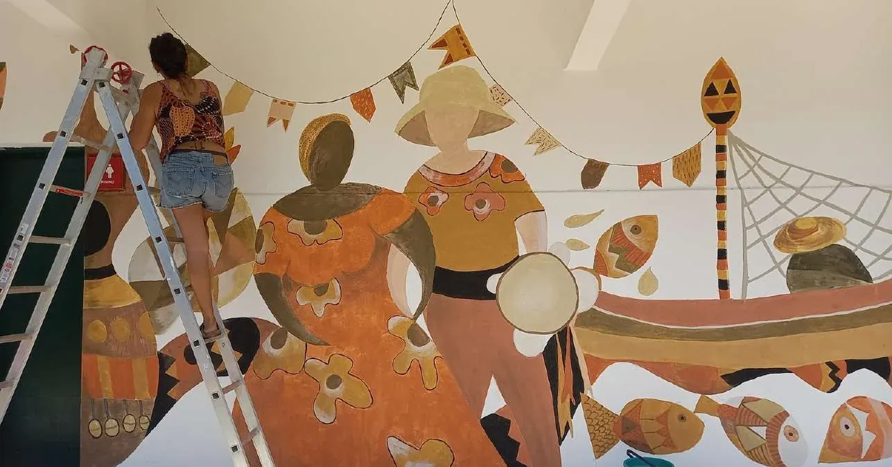Grupo de participantes pintando juntos um mural coletivo em tintas de terra