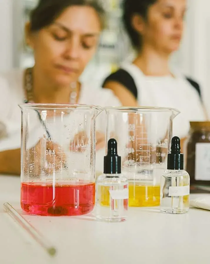 Béqueres com extratos de corante natural rosa e amarelo sobre a bancada da oficina